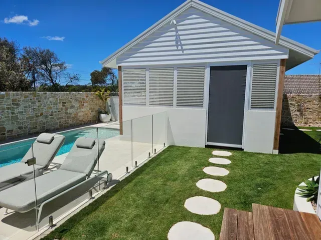 Poolside cabana with lounge chairs and stone pathway.