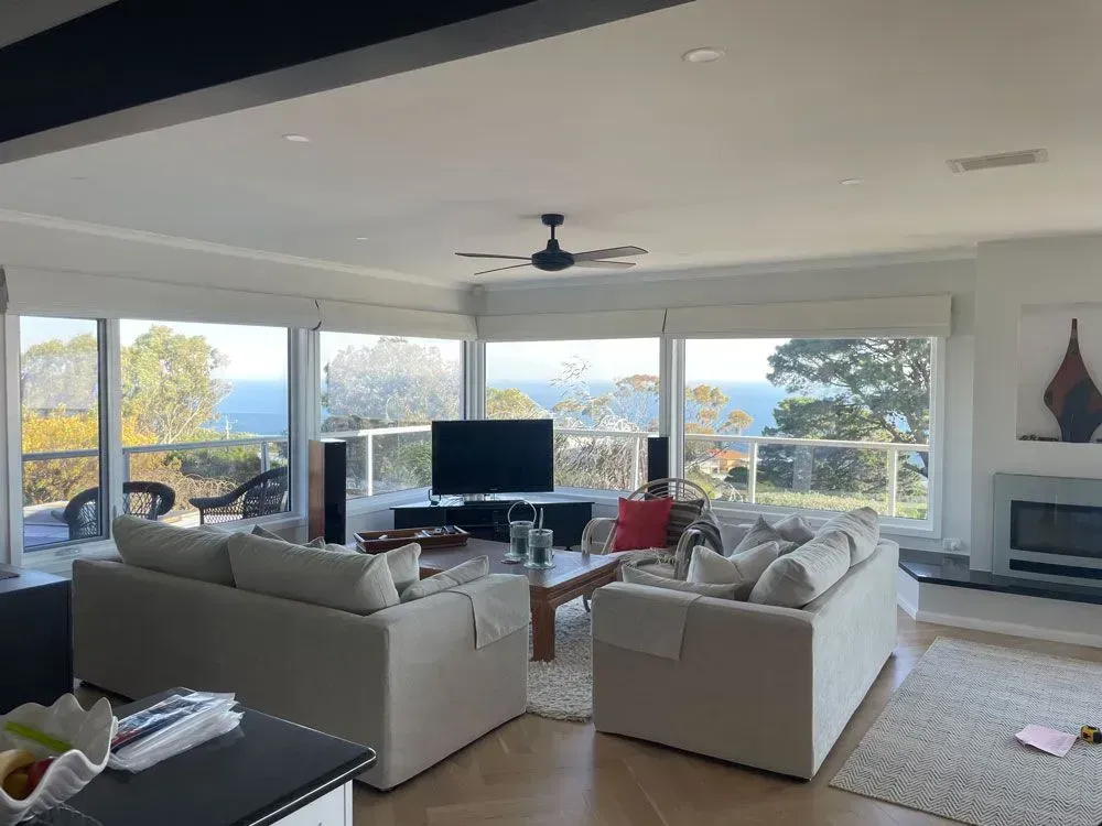 Spacious living room with ocean view, two light sofas, a coffee table, and large windows.