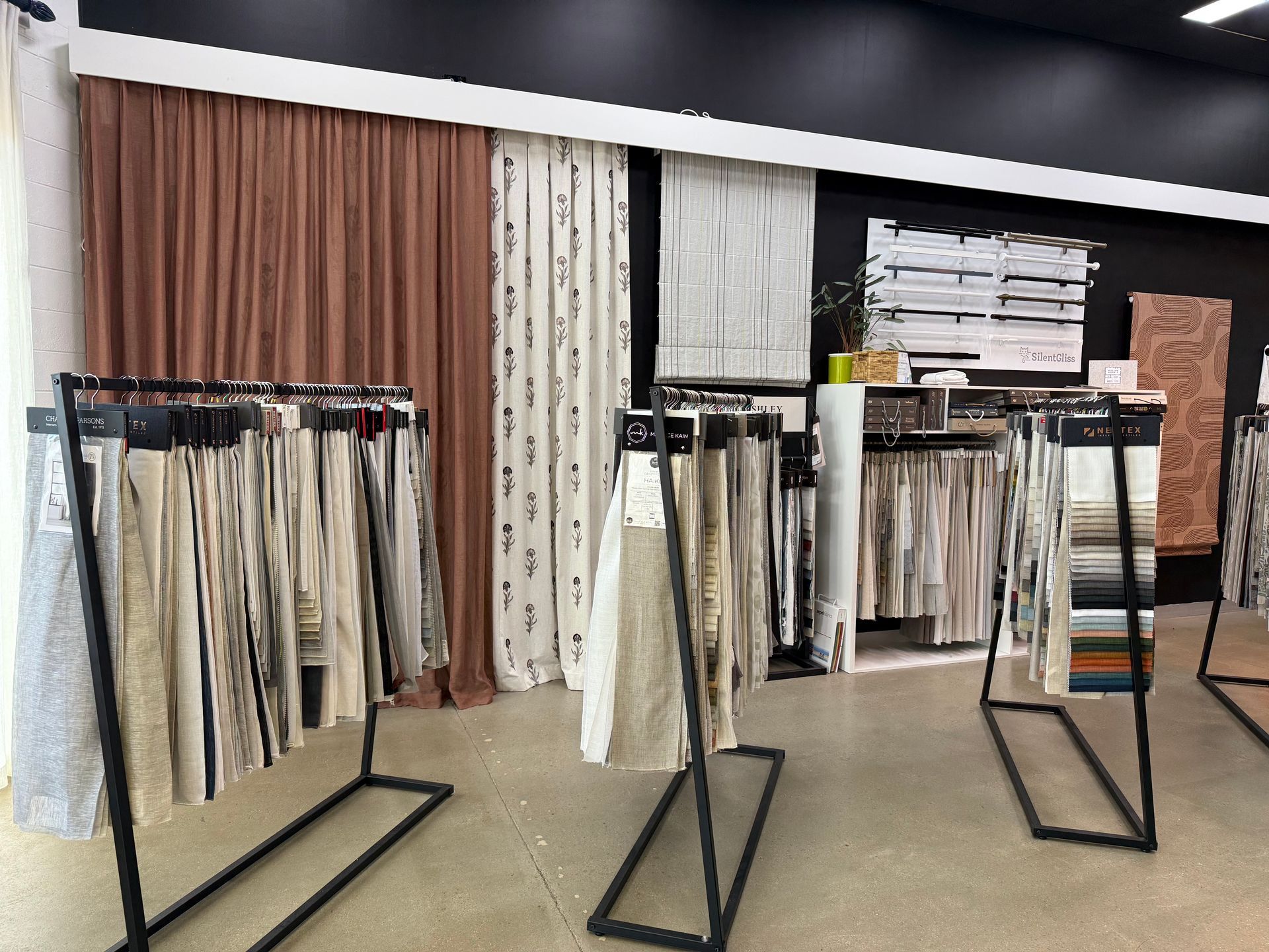 Fabric swatches displayed on black metal racks in a showroom.