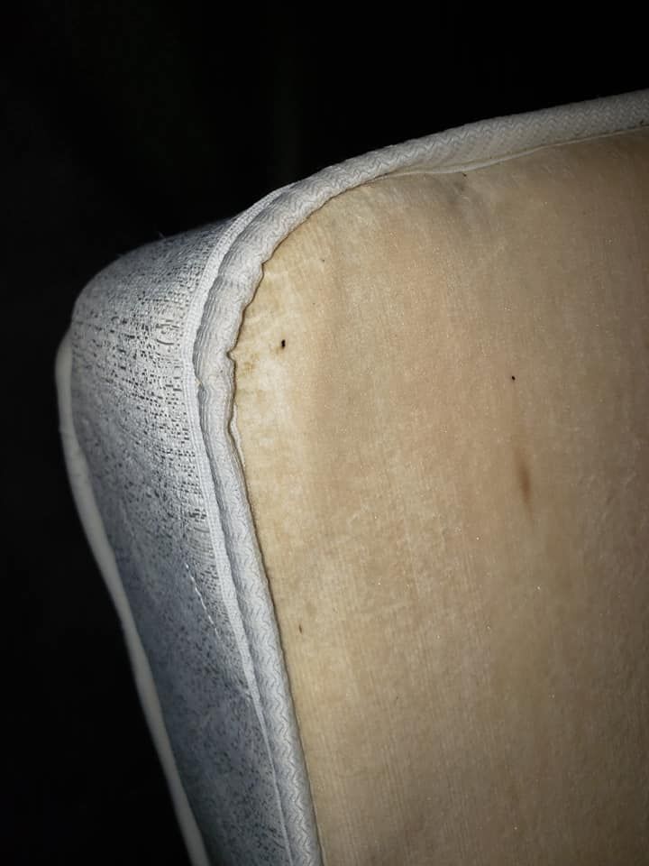 Corner of a mattress showing discolored fabric and a small tear in the edge.