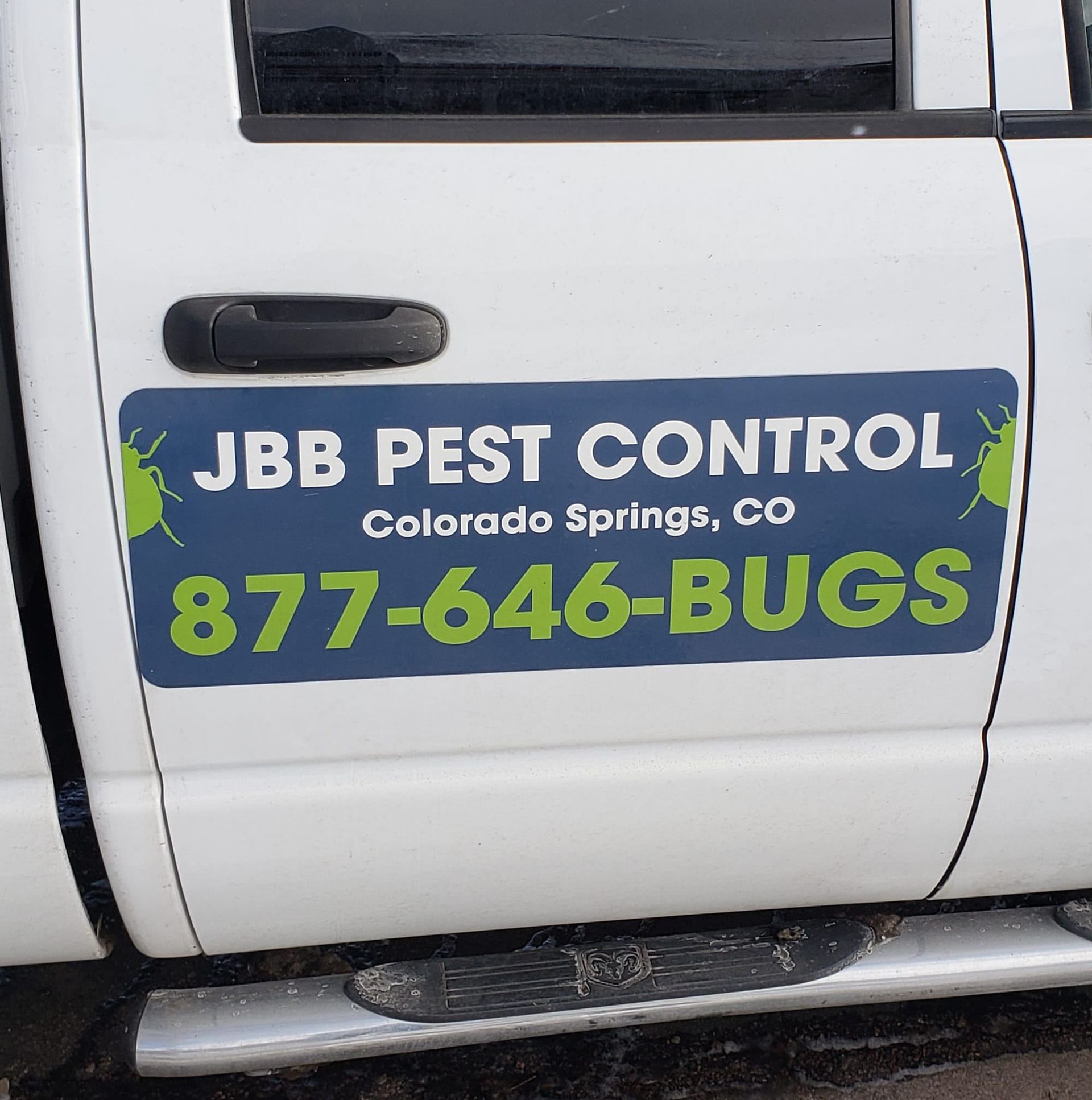 White truck door with JBB Pest Control advertisement: company name, location, phone number.