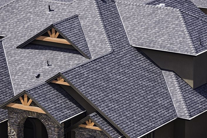 Close-up of gray shingled rooftops with dormer windows and exposed wooden trusses