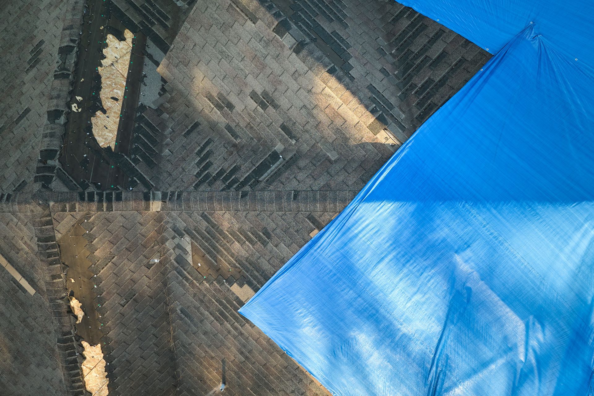 Abstract aerial view of blue tarps covering patches of brown and gray farmland