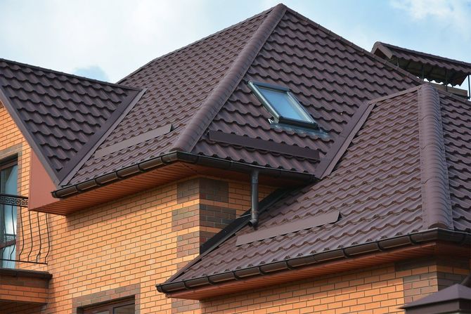 Brick house with dark brown tiled roof and skylight against a cloudy sky