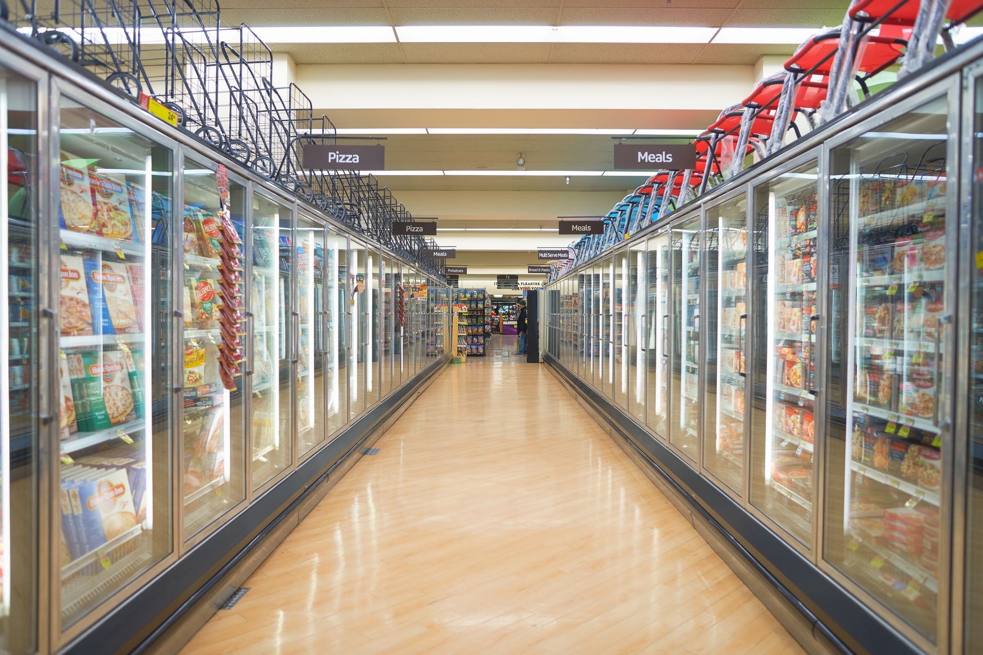 A supermarket freezer aisle with glass-doored cases on both sides and a polished floor.