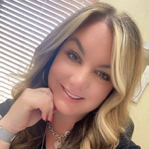 A woman wearing a necklace and earrings is smiling for the camera.