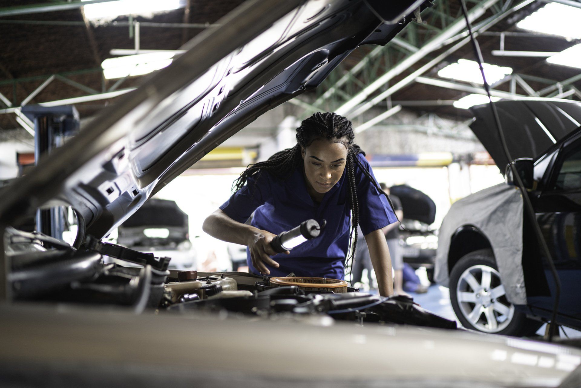 A woman with a blue shirt looking at the front engine | Sydney, NSW | Autocure Mobile Mechanics