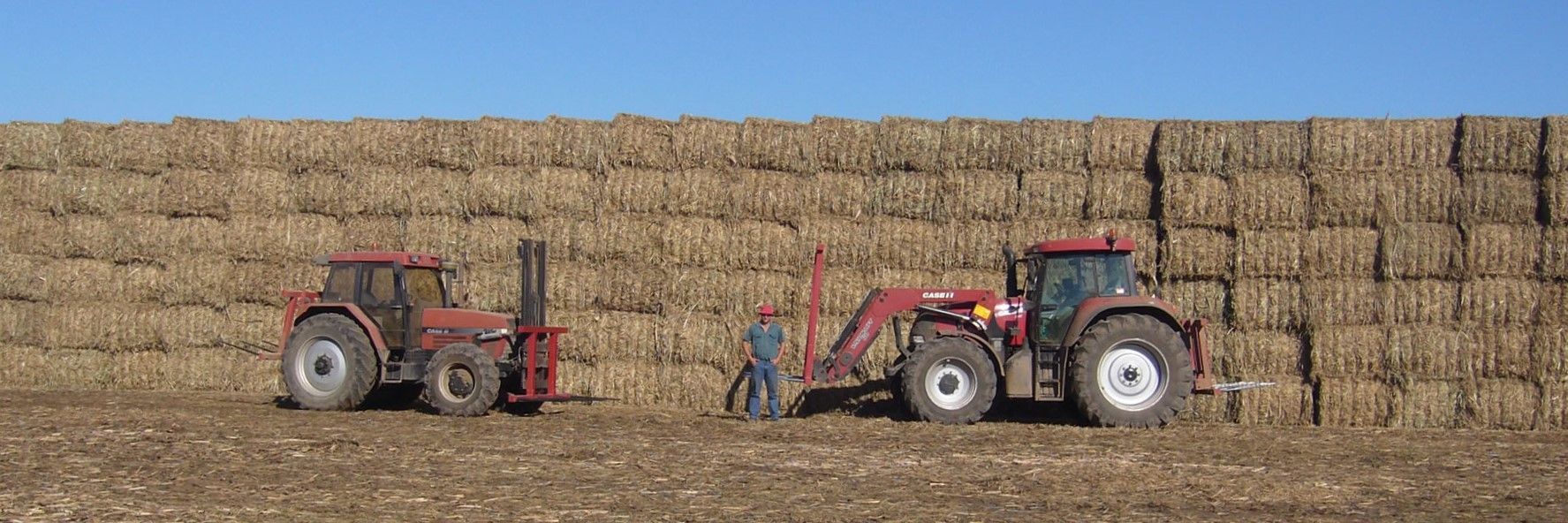 Two Tractors On A Farm With Mulch Bales — Cooroy Produce In Cooroy, QLD