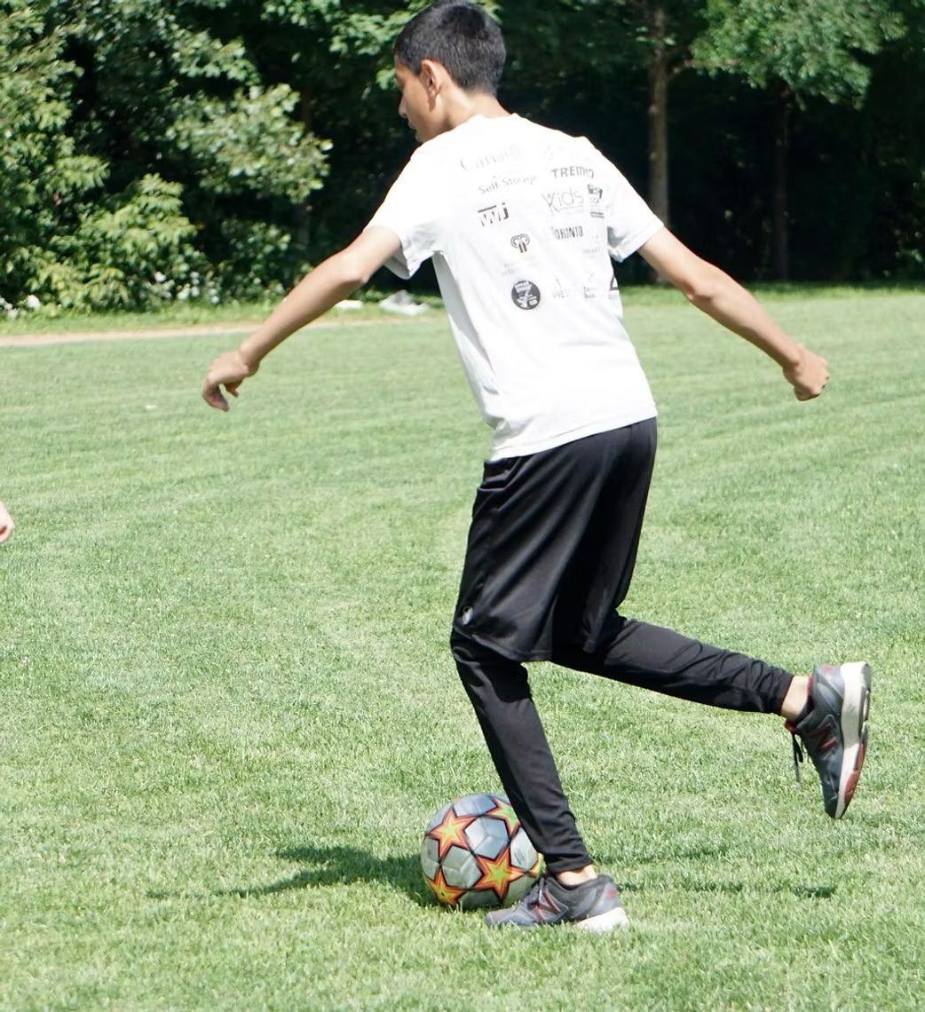 A boy in a white shirt is kicking a soccer ball A boy in a white shirt is kicking a soccer ball