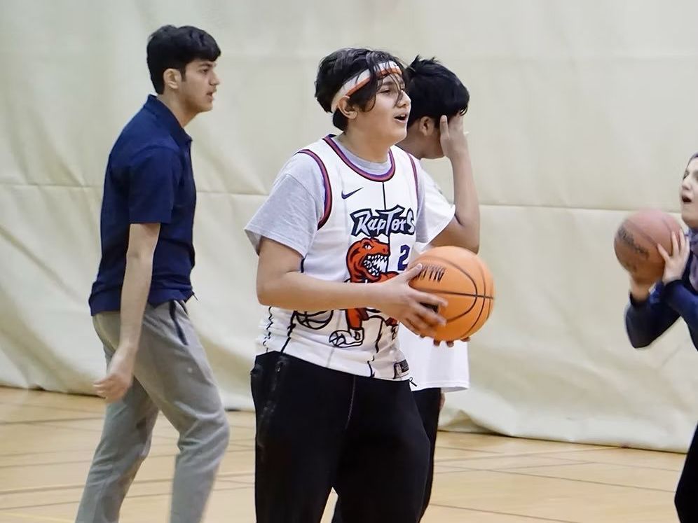 A group of people are playing basketball in a gym. A group of people are playing basketball in a gym.