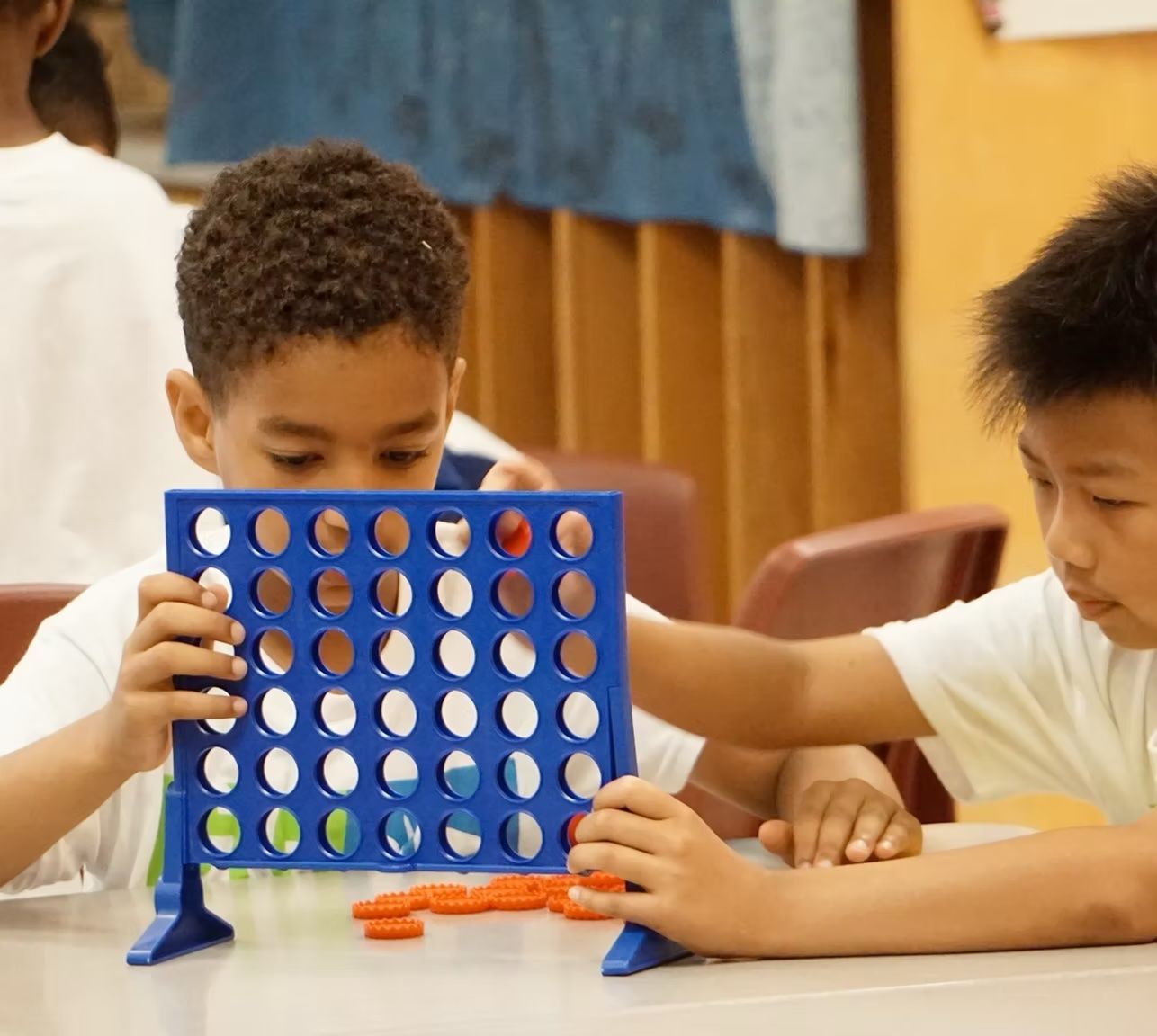 Two young boys are playing a game of connect four