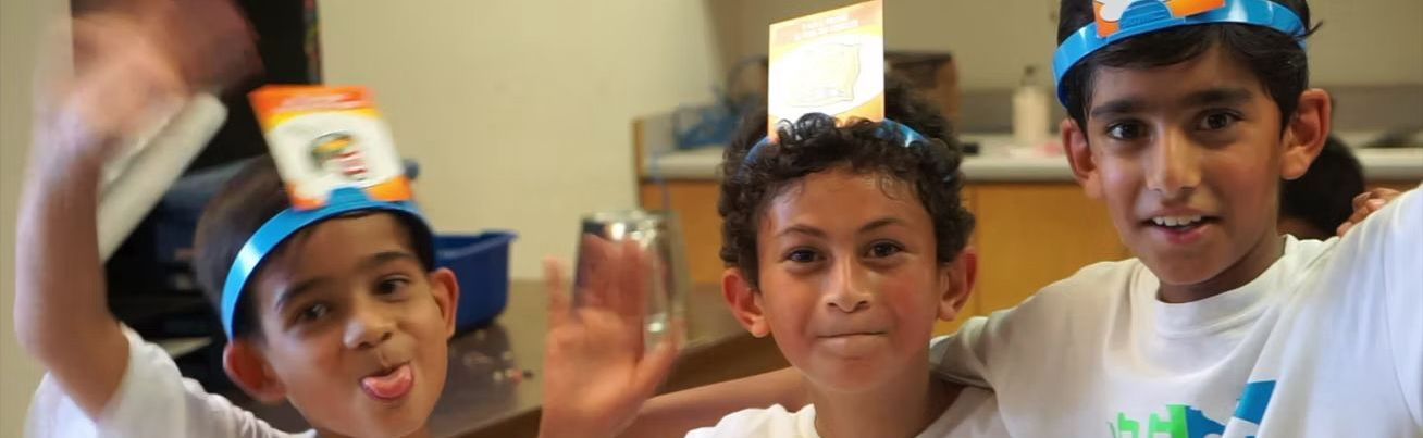 Three young boys wearing crowns on their heads are posing for a picture.