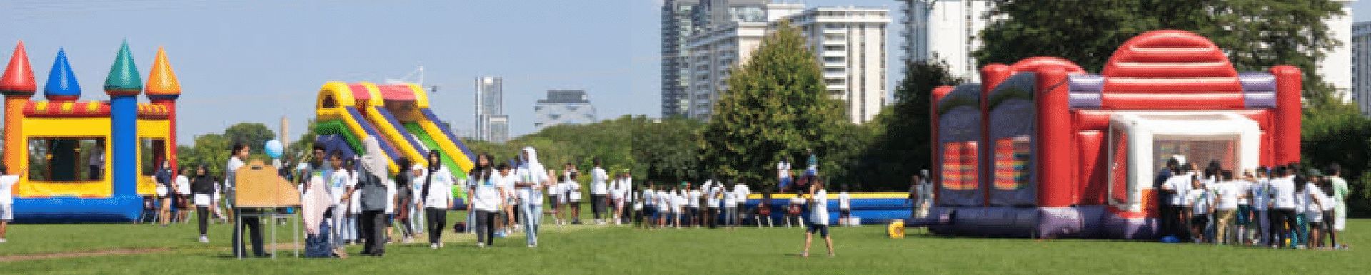 A group of people are standing in front of a row of bouncy houses