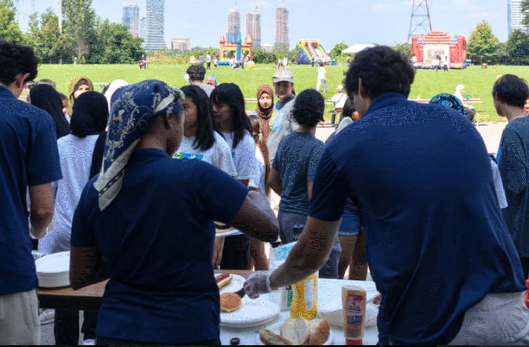 A group of people are standing around a table eating food.