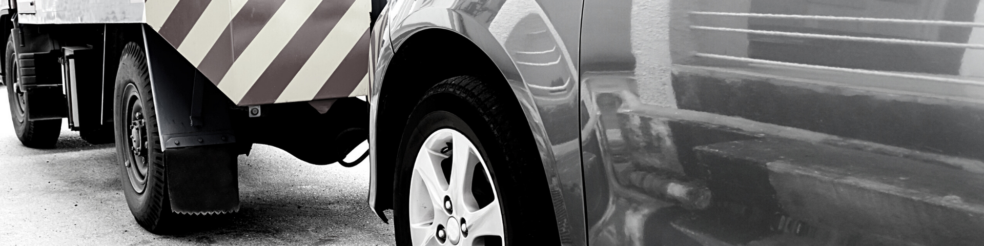 Close-up of a tow truck with a vehicle's tire and reflective striping.