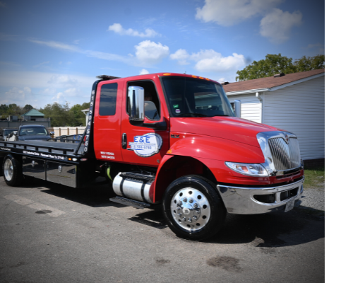 Red tow truck parked outdoors on a sunny day.