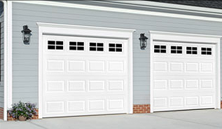 There are two white garage doors on the side of a house. A couple of white garage doors on the side of a house.