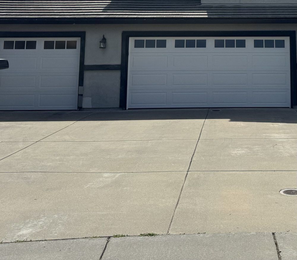 Two white garage doors in front of a house