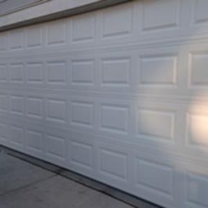 A white garage door is sitting on the side of a house.