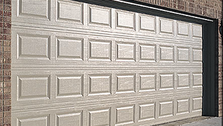 A white garage door is open on a brick wall.