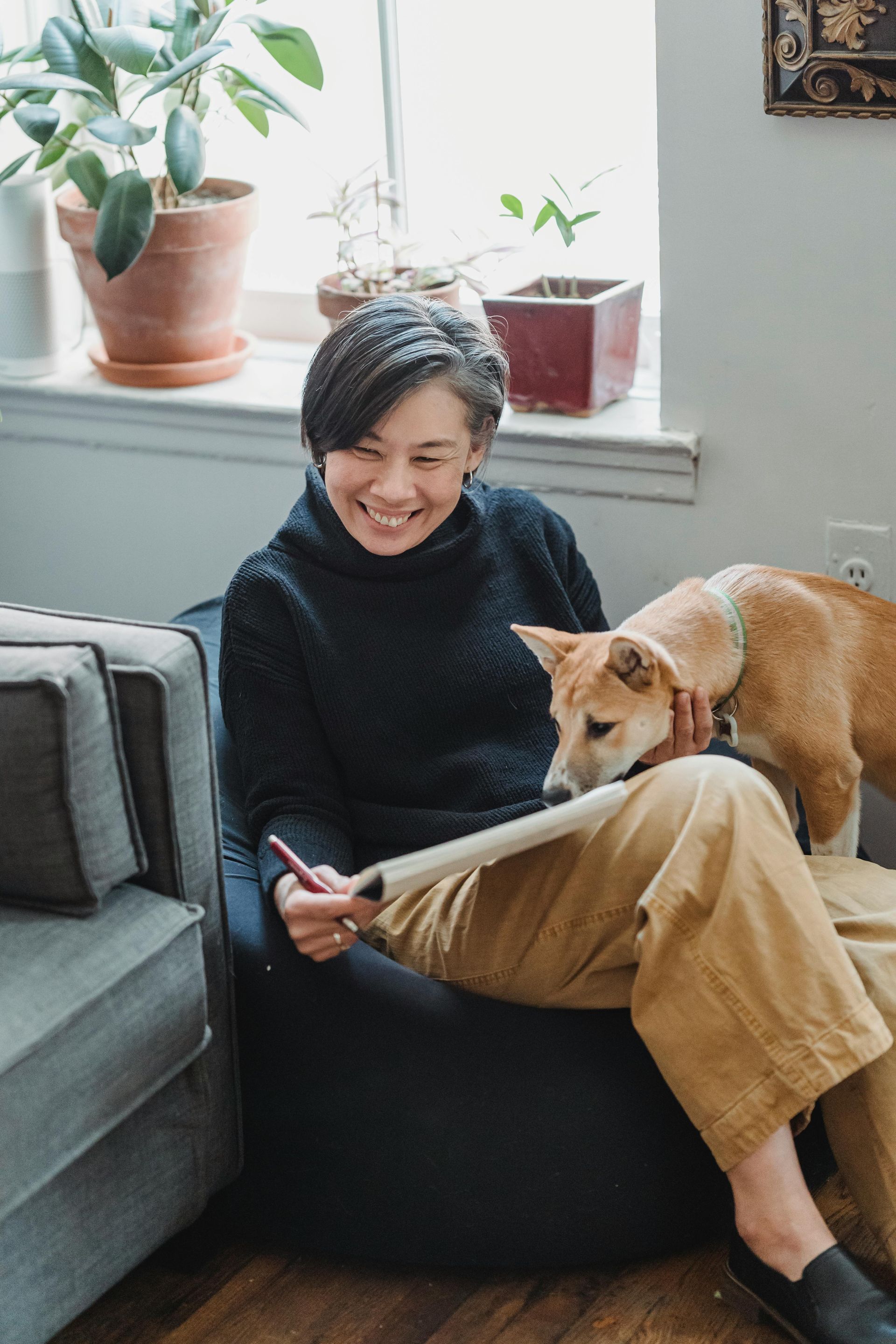 A woman is sitting in a chair with a dog on her lap.