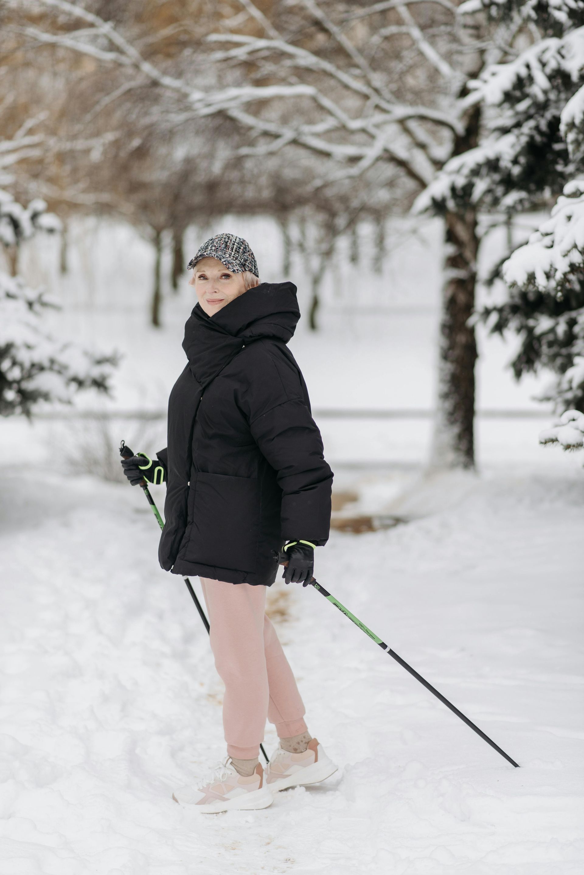 A woman is standing in the snow holding skis.