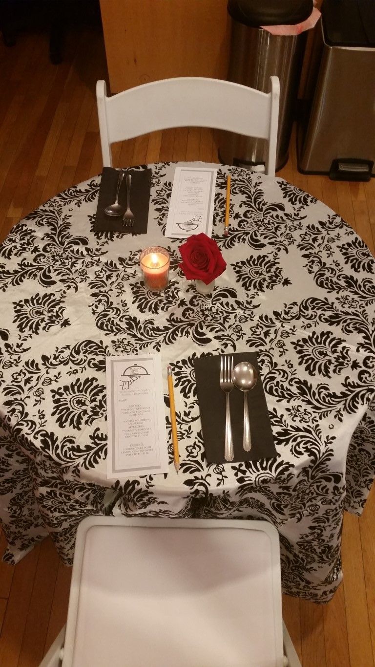 A table with a black and white tablecloth and a candle on it.