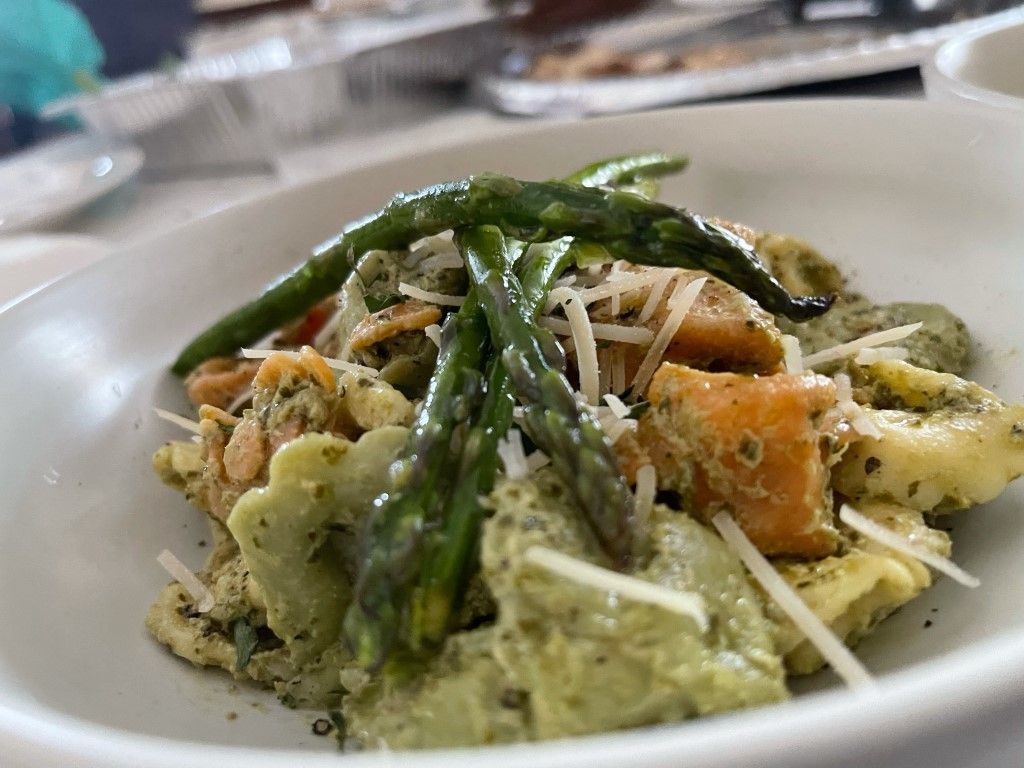 A bowl of pasta with asparagus and cheese on a table.