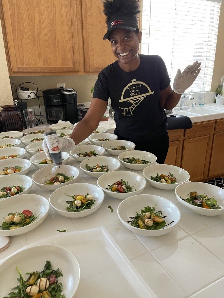 A woman is standing in front of a table filled with bowls of food.