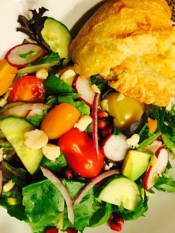 A white plate topped with a salad and a piece of bread