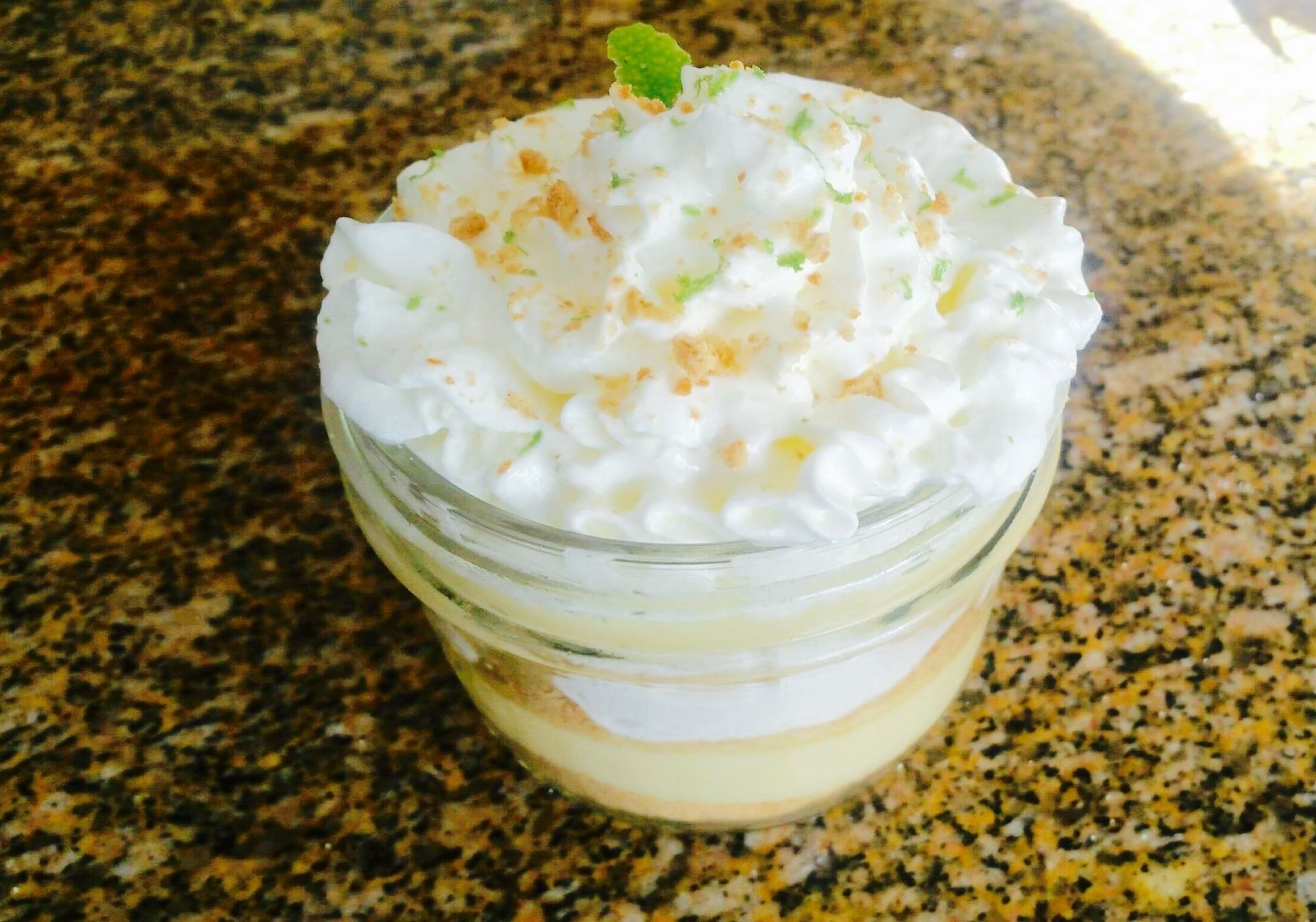 A mason jar filled with a dessert with whipped cream on top.
