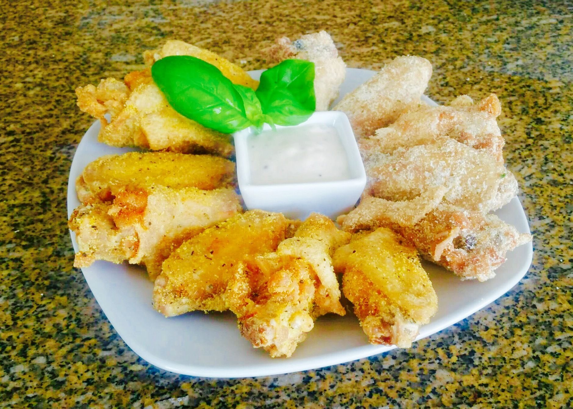 A white plate topped with fried chicken wings and a dipping sauce.