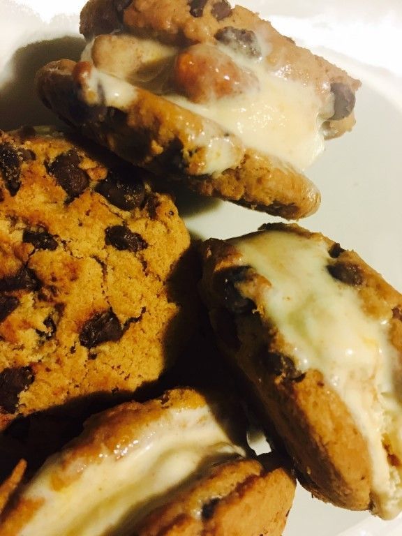 A white plate topped with chocolate chip cookies and ice cream sandwiches