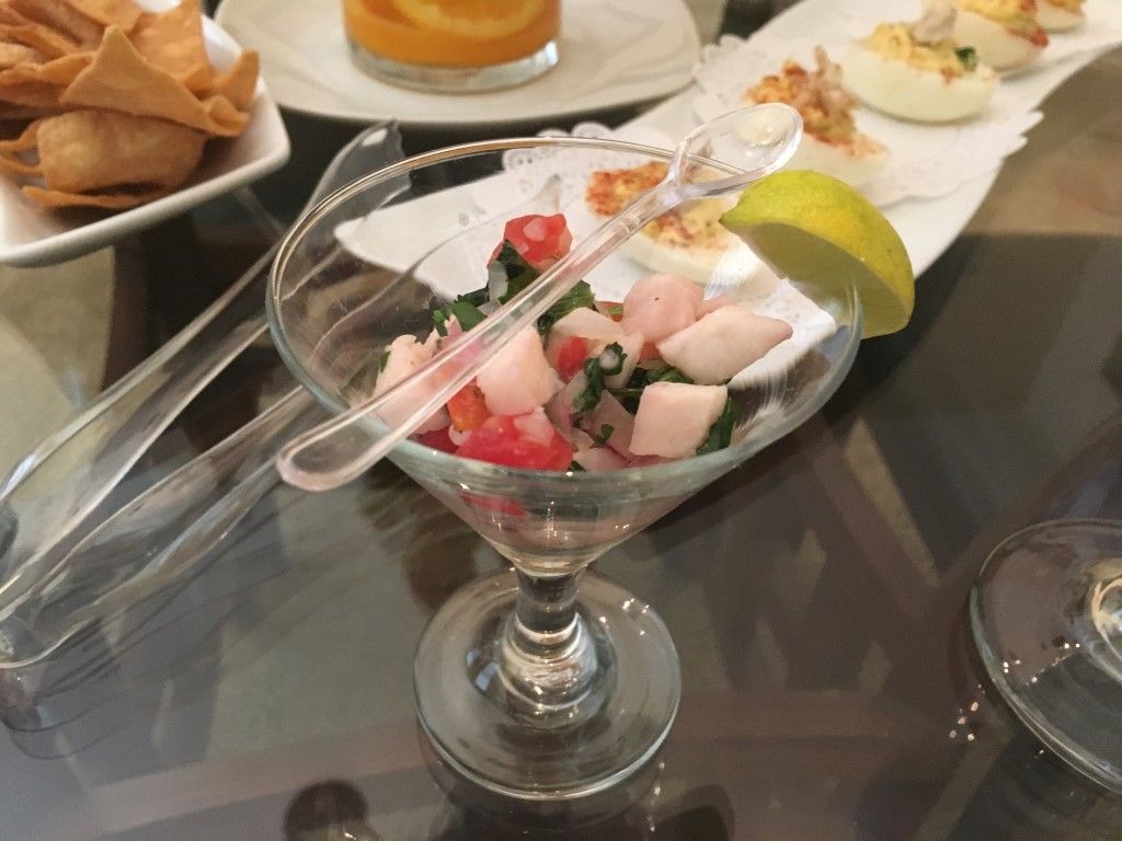 A martini glass filled with food and tongs on a table