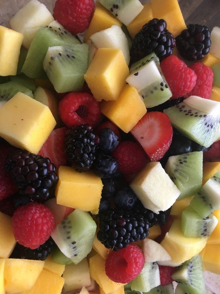 A close up of a fruit salad with kiwi strawberries and raspberries