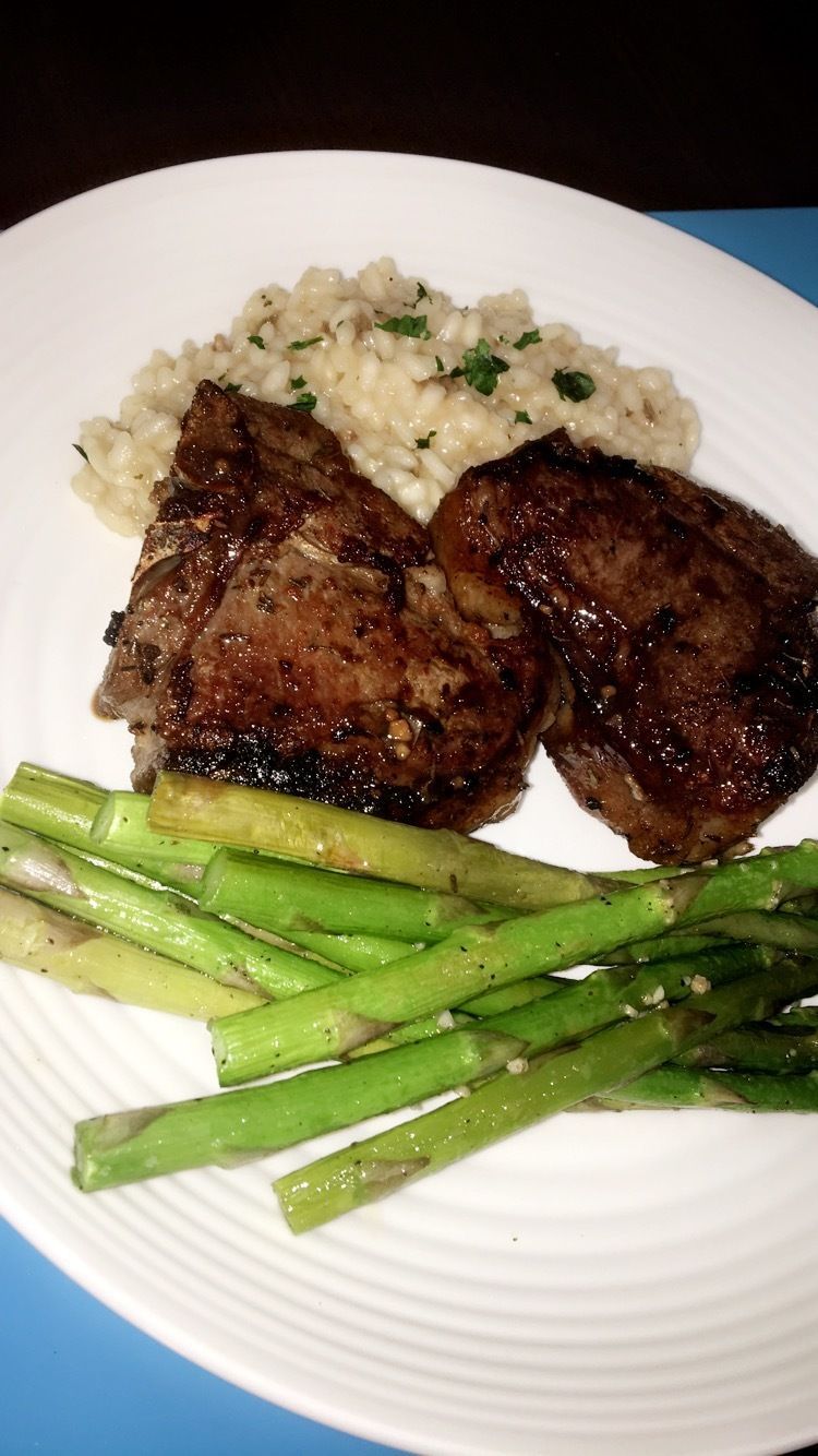 A white plate topped with meat and asparagus on a blue table.