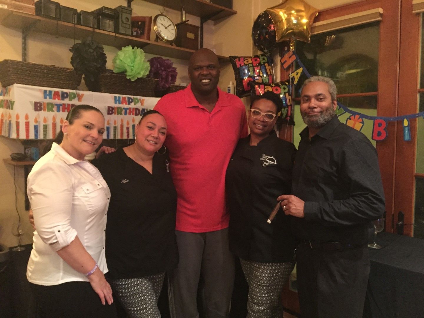 A group of people posing for a picture in front of a happy birthday banner