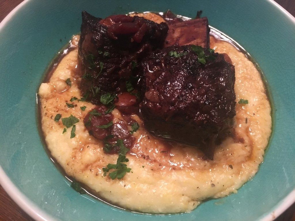 A blue bowl filled with mashed potatoes and meat