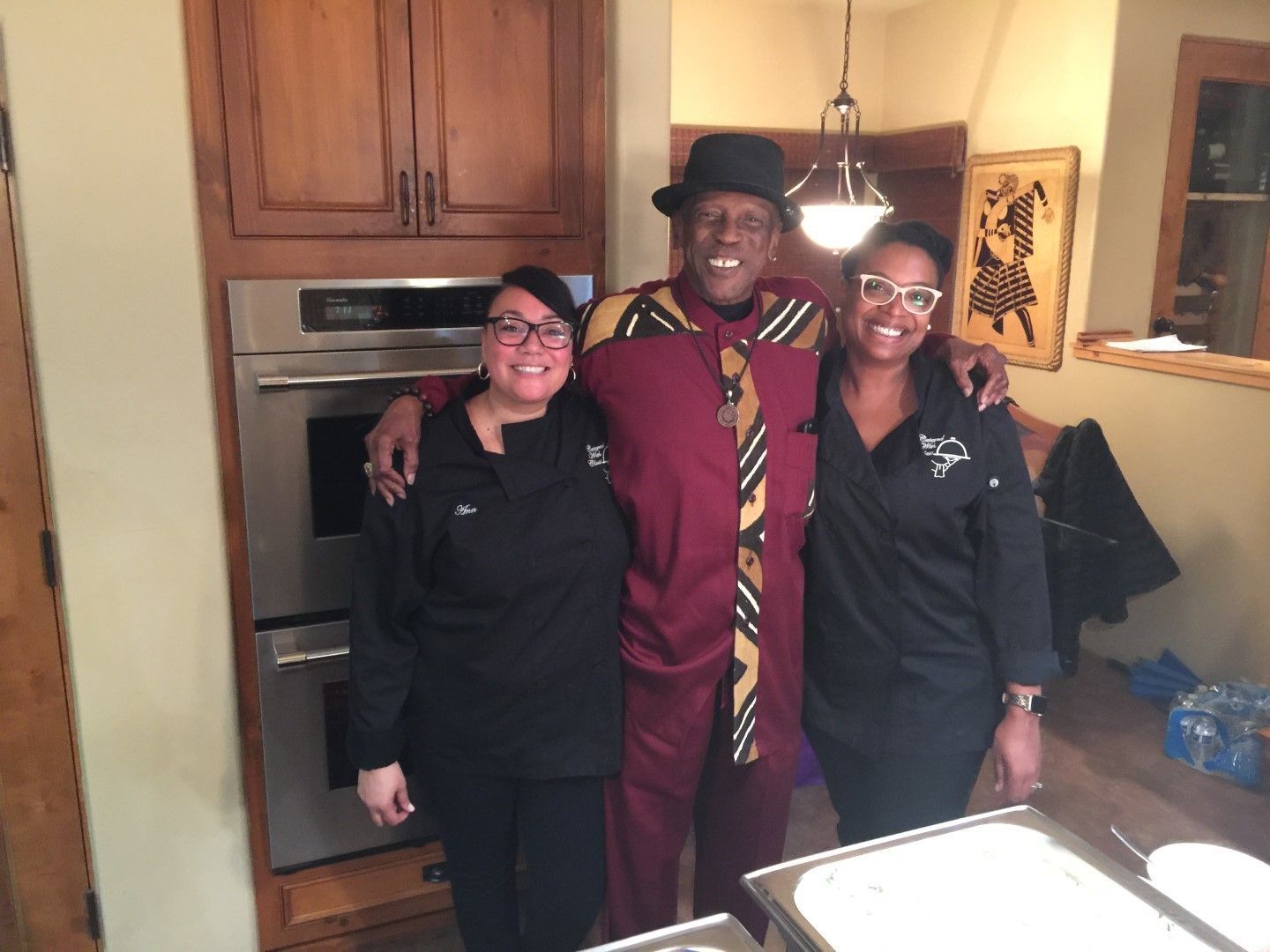 A man and two women are posing for a picture in a kitchen