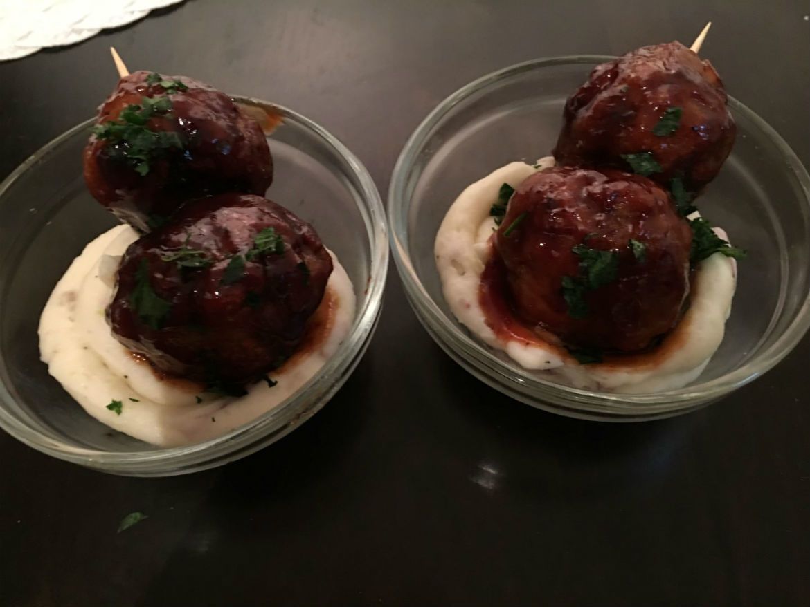Two bowls of meatballs and mashed potatoes on a table