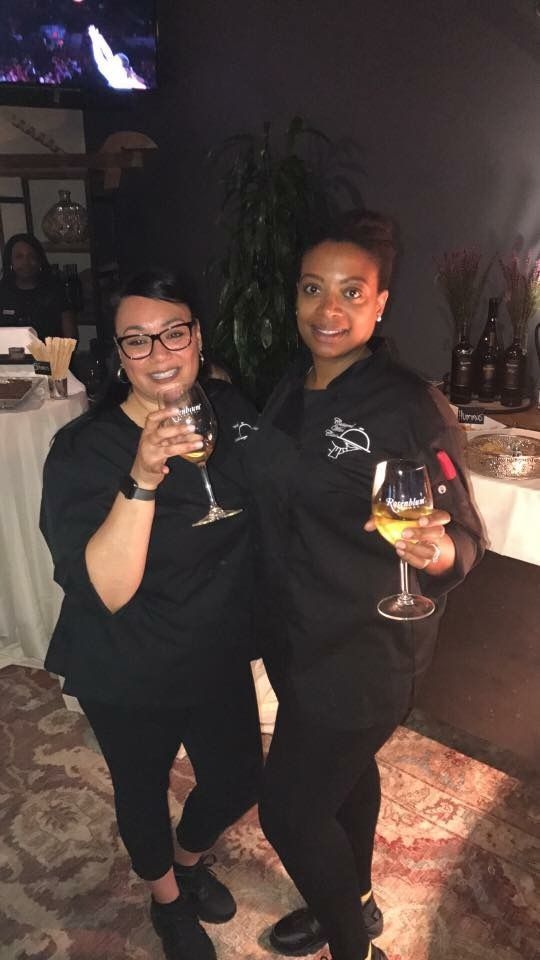 Two women are standing next to each other holding wine glasses.