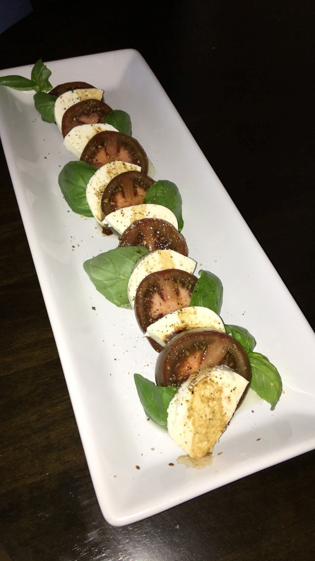 A white plate topped with sliced tomatoes and mozzarella.