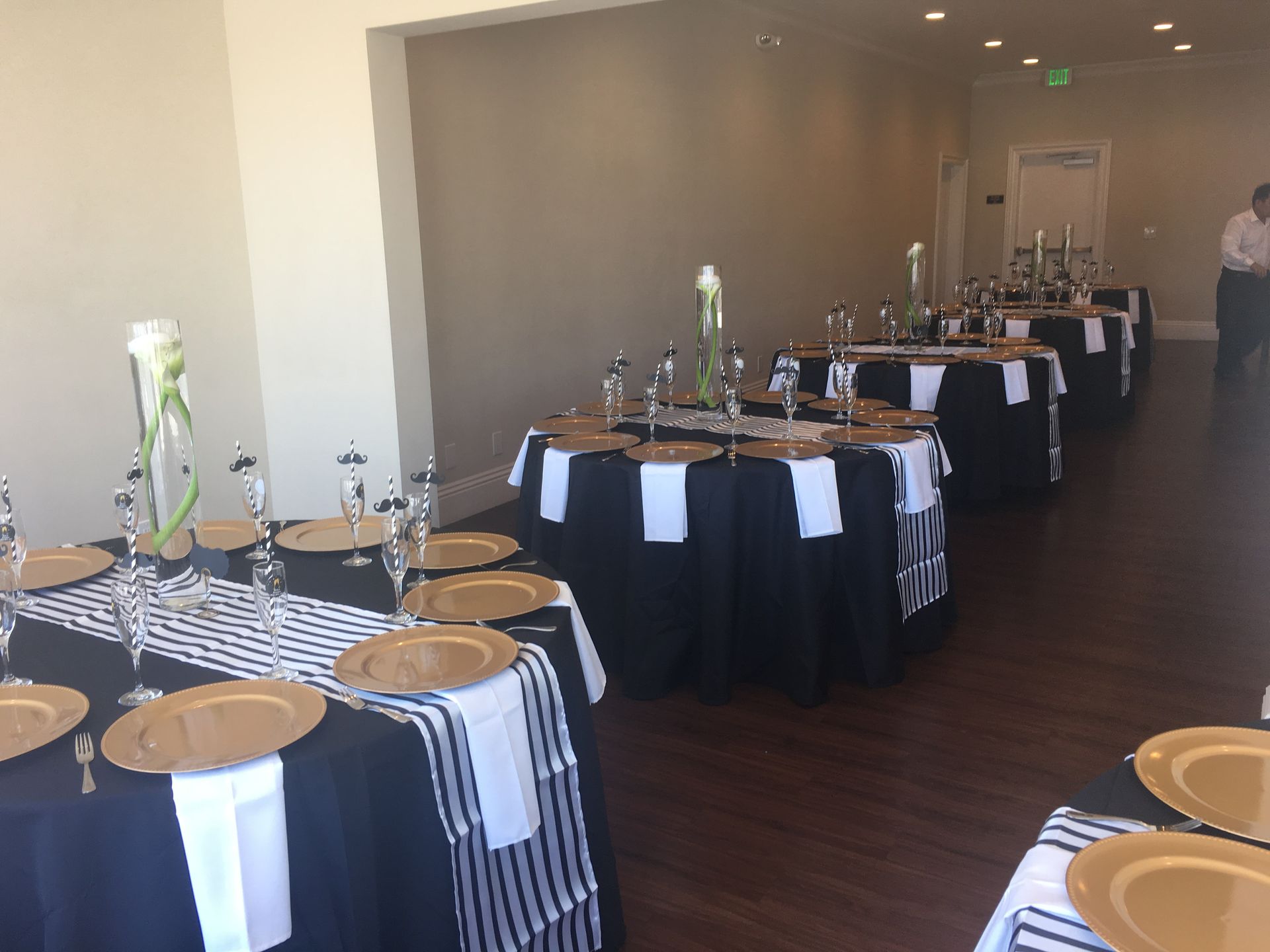 A room filled with tables and plates and a man standing in the background
