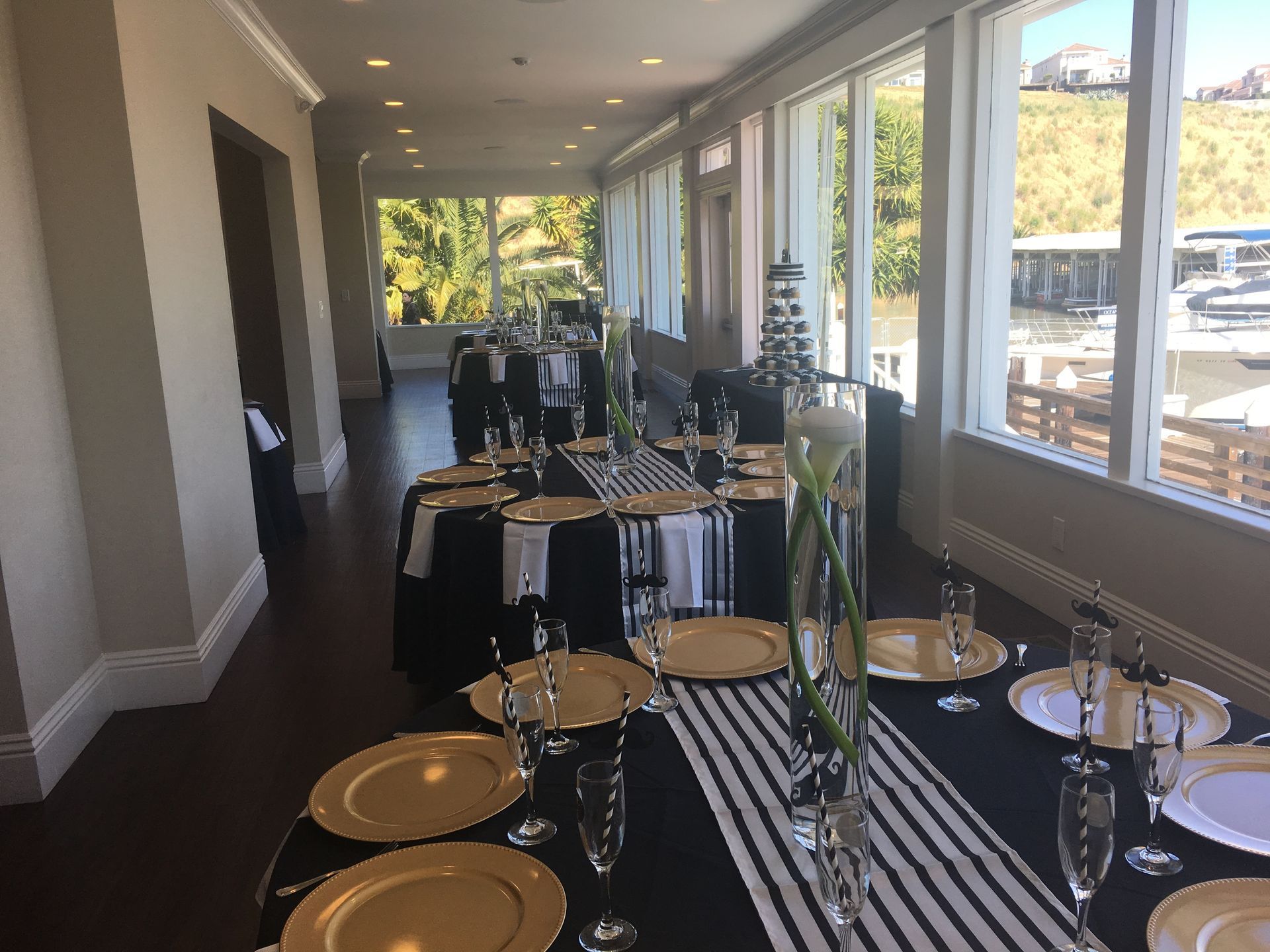 A long table with plates , glasses , and a striped table runner.