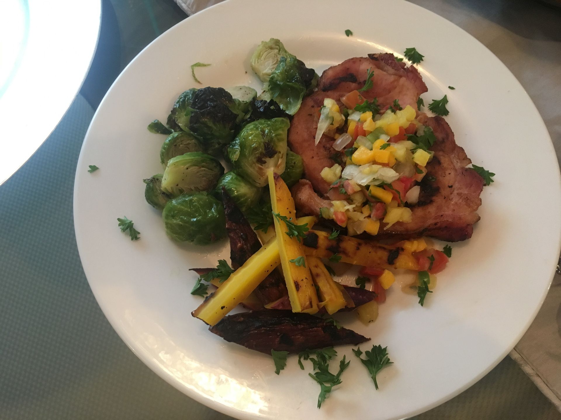 A white plate topped with meat and vegetables on a table