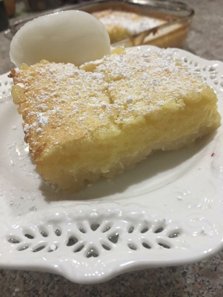 A white plate topped with a piece of cake and powdered sugar.