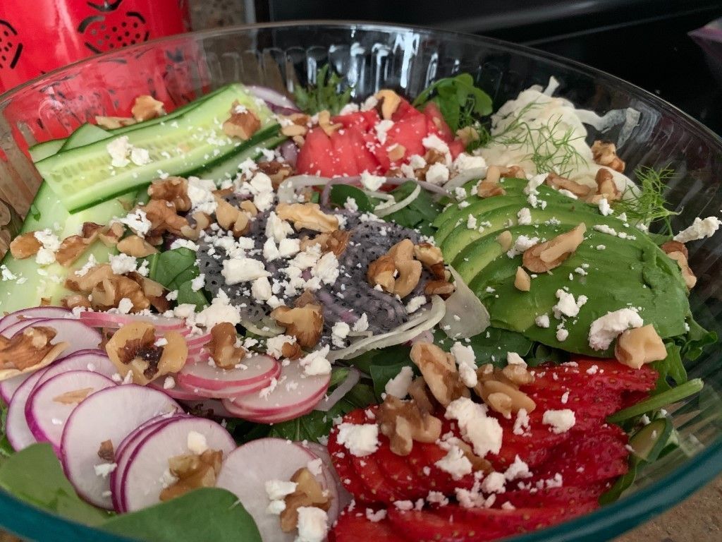 A glass bowl filled with a salad of vegetables and nuts