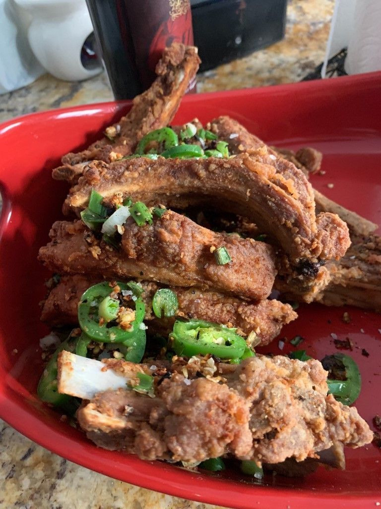 A red plate topped with fried pork ribs and green peppers.