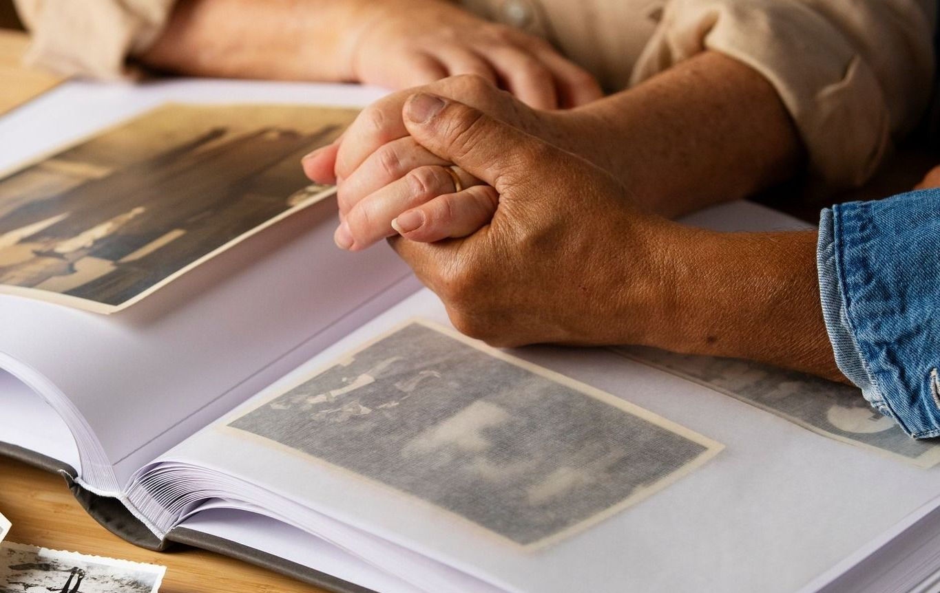 a person holding another person 's hand while looking at a photo album after Bereavement of a loved one 