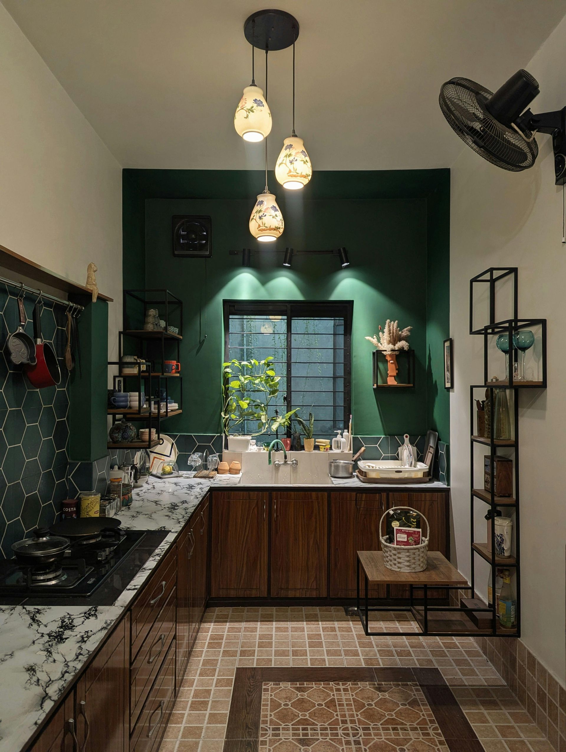 Modern kitchen with dark cabinets, green accent wall, pendant lights, and a window over the sink